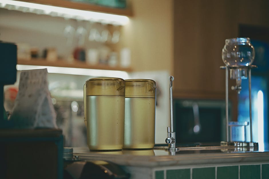A cozy coffee shop interior featuring brewing equipment and two jugs of water on the counter.